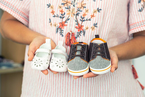 Terhes nő gazdaság kis baba lány és egy fiú cipő - Fotó, kép