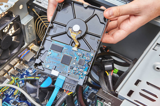 Repairman is installing an internal hard drive of the desktop PC, close up. - Φωτογραφία, εικόνα