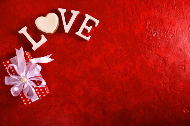Composition for Valentine's Day on a red background with white letters and a heart. Top view. - Photo, Image