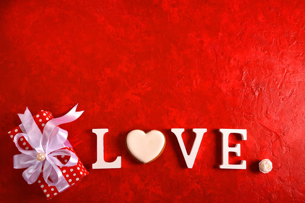 Composition for Valentine's Day on a red background with white letters and a heart. Top view. - Foto, imagen