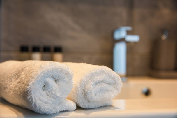 Interior del baño. Fregadero desenfoque y rollos blancos de toallas de mano. Vista de primer plano con detalles
 - Foto, Imagen