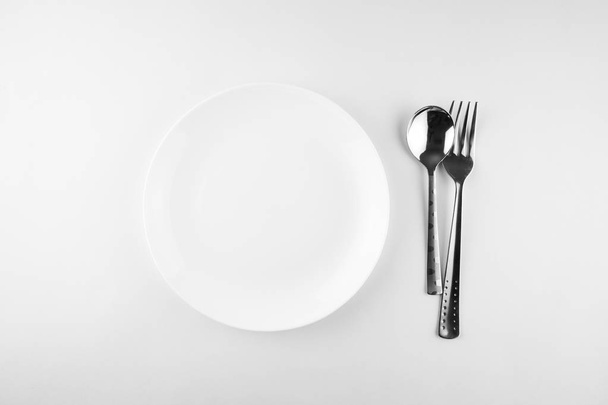 Top view of empty white food plates, fork and spoon - Photo, image