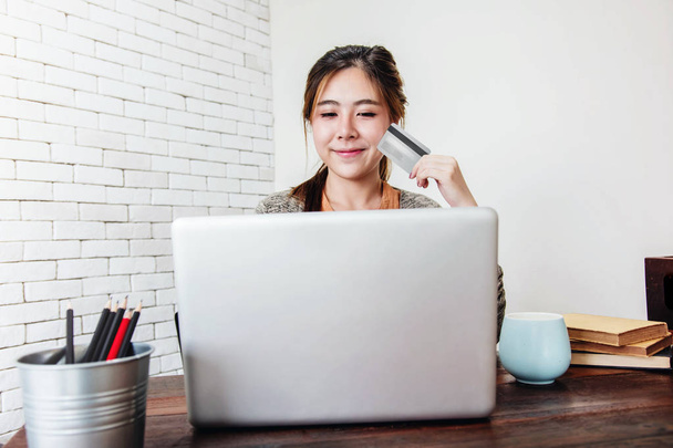 Mujer joven de compras o hacer el pago con tarjeta de crédito y ordenador portátil en casa, productos de compra femenina feliz a través de Online
 - Foto, Imagen