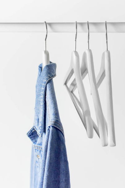 Sininen denim takki valkoinen puinen takki ripustin sauva vastaan vaaleanharmaa seinä tasainen lay kopio tilaa. Denim, muodikas takki, naisten tai miesten trendi vaatteet, muoti tausta. Kaupan konsepti, myynti
 - Valokuva, kuva