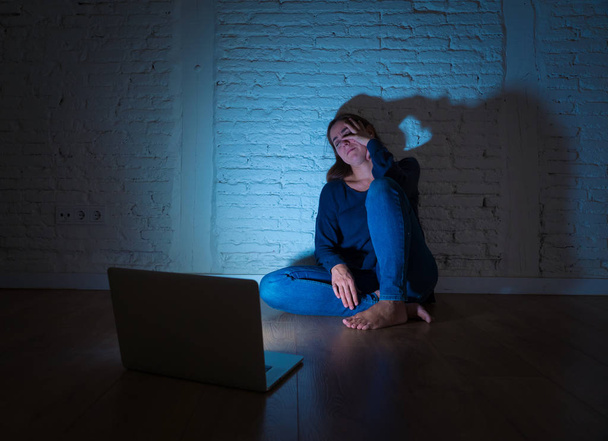 Sad and scared female Young woman with computer laptop suffering cyberbullying and harassment being online abused by stalker or gossip feeling desperate and humiliated in cyber bullying concept. - 写真・画像
