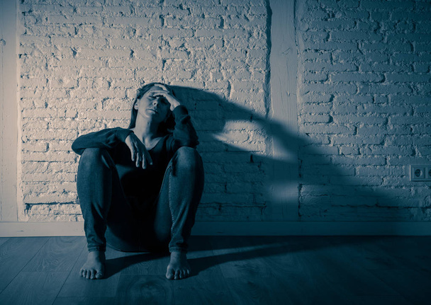 Young devastated depressed woman crying feeling hurt suffering depression in Sadness Emotional pain and Human Expression and Loneliness and heartbroken concept with copy space and dramatic dark light. - Photo, image