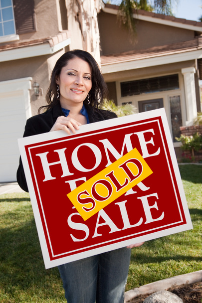 House and Woman Holding Sold Home Sign - 写真・画像