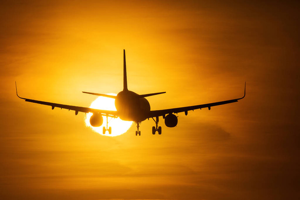 Silhouette d'un avion au-dessus du soleil avec de beaux nuages rouges en arrière-plan
 - Photo, image