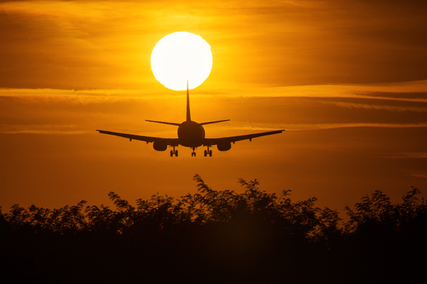 Silhouette di un aereo aereo vicino al sole con bellissime nuvole rosse sullo sfondo
 - Foto, immagini