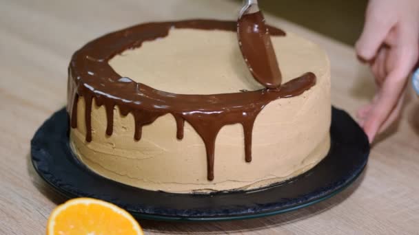 Szakács összenyomja a krém. Csokoládé hab a tortán. Fehér torta borított a csokoládé és a krém. Csokoládé torta díszítését. - Felvétel, videó