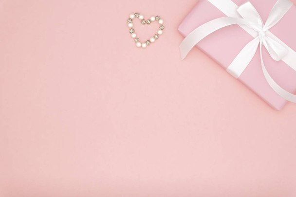 Valentin vagy a nők napi rózsaszín ajándék íj fehér szalaggal díszített kis szívét, korall papír alapon. Koncepció dekor szerelem nap vagy születésnap. Lapos feküdt. Másolja a hely - Fotó, kép