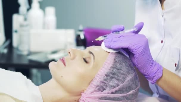 Cosmetologist makes the rejuvenating facial injections procedure on the face skin in a beauty salon - Materiaali, video