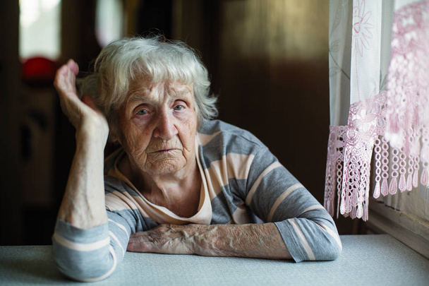 Portrait of a pensioner russian woman at the table in home. - Photo, Image