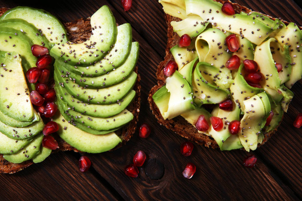 avocado en rijpe granaatappels gesneden op toast brood met kruiden en avocado  - Foto, afbeelding