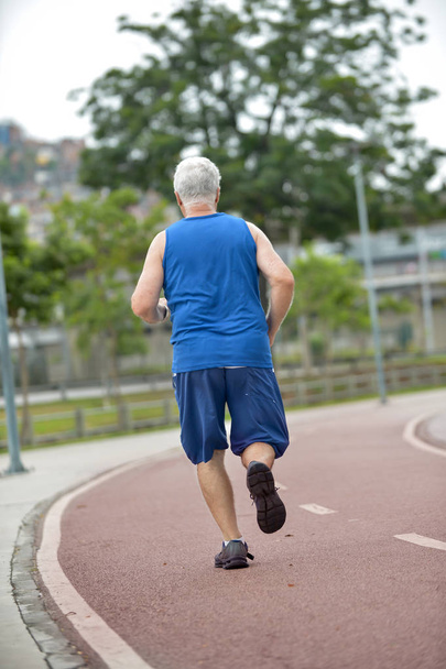 Senior läuft als körperliche Aktivität auf der Rennstrecke - Foto, Bild