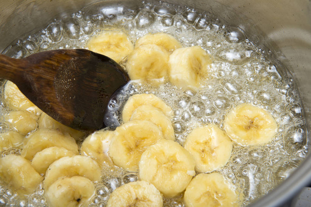 banana doce sendo cozida em uma panela de aço inoxidável em um xarope de açúcar
 - Foto, Imagem