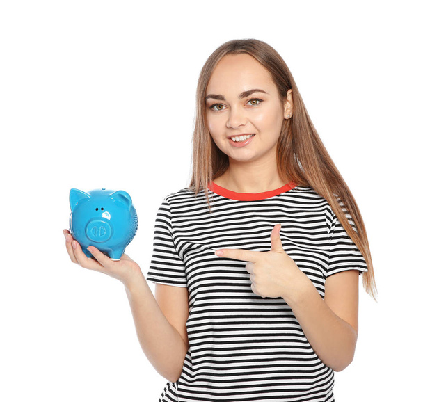 Young woman with piggy bank on white background - 写真・画像