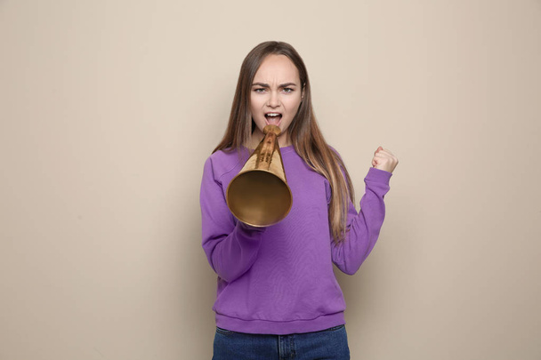 Young emotional woman with megaphone on color background - Foto, immagini