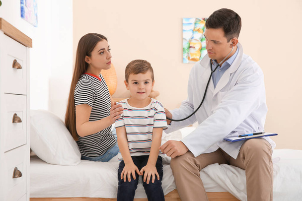 Children's doctor examining little patient with stethoscope at home - Photo, Image
