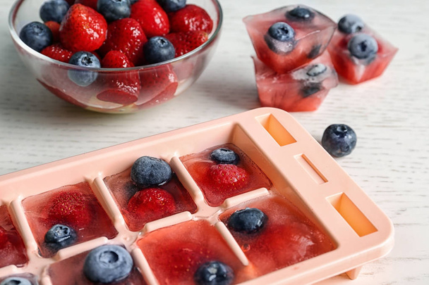 Ice cubes with berries in tray on table, closeup - Foto, Imagem