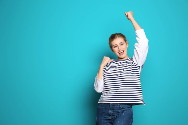 Happy young woman showing thumbs up on color background. Celebrating victory - 写真・画像