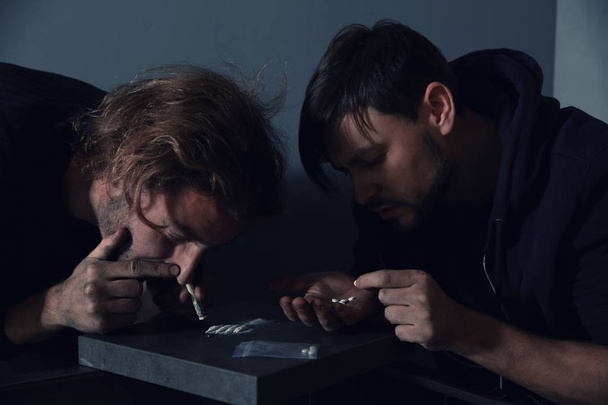 Young addicted men taking drugs on grey background - Fotó, kép