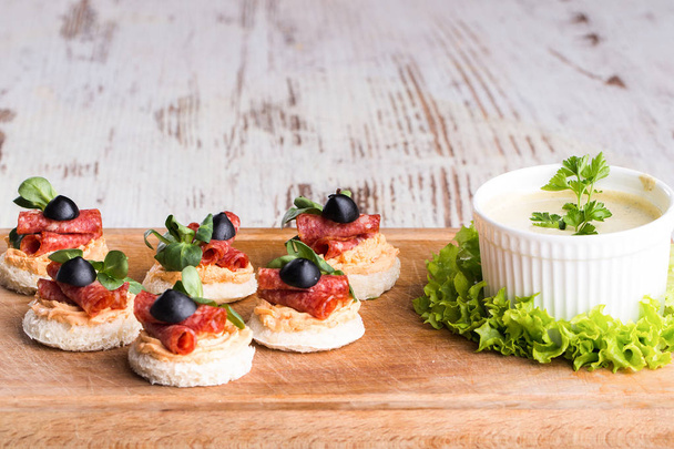 Вкусные канапе с салями, оливками и специями на деревянном фоне - Образ. Копирование пространства
 - Фото, изображение