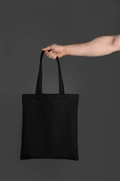 Man holding cotton shopping eco bag on grey background. Mockup for design - Photo, image