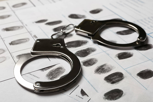 Police handcuffs and criminal fingerprints card, closeup - Valokuva, kuva