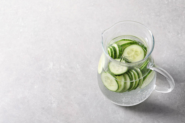Jug of fresh cucumber water on grey background. Space for text - Foto, imagen