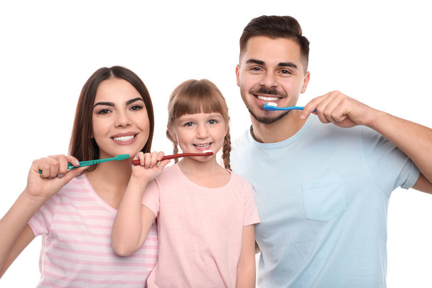 Little girl and her parents brushing teeth together on color background - Fotoğraf, Görsel