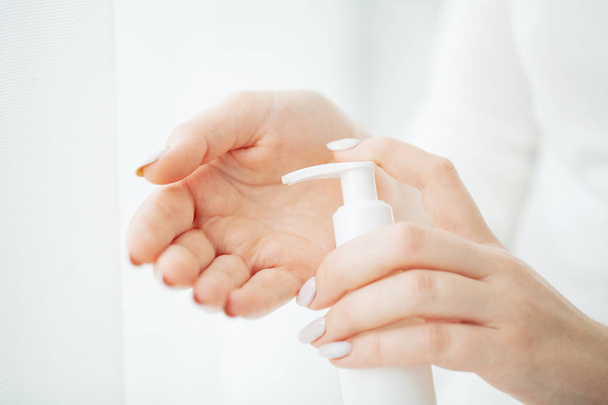 手肌のケア。柔らかい絹のような健康的な肌に化粧品のハンド クリームを適用する自然なマニキュア爪美人手クリーム チューブを保持している女性の手のクローズ アップ - 写真・画像