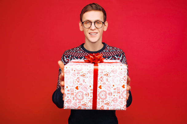 A man with glasses holds out a gift box to the camera - Fotoğraf, Görsel