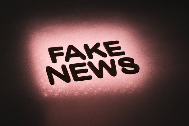 palabra "noticias falsas" escrito en letras de madera e iluminado por el fondo en la luz de fondo
 - Foto, Imagen