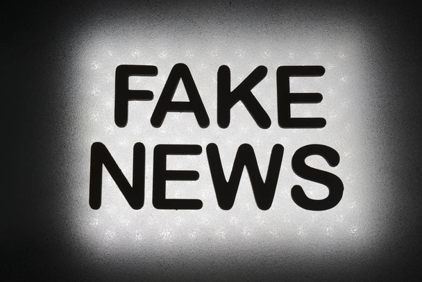 palavra "fake news" escrito em letras de madeira e iluminado por fundo em backlight
 - Foto, Imagem