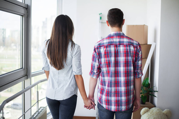 New Home. Funny young couple enjoy and celebrating moving to new home. Happy couple at empty room of new home - Foto, Imagem