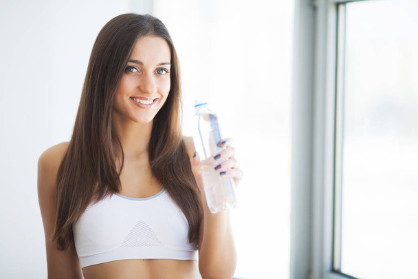 Здоровый образ жизни. Молодая женщина держит в руках бутылку с водой
 - Фото, изображение