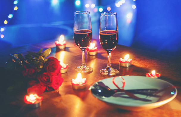 ロマンチックなバレンタイン ディナー コンセプトが大好き/木製テーブル ディナー夜赤いハート フォーク スプーン プレートとカップルのシャンパン グラス ワイン バラのキャンドルで飾られたロマンチックなテーブルセッティング - 写真・画像