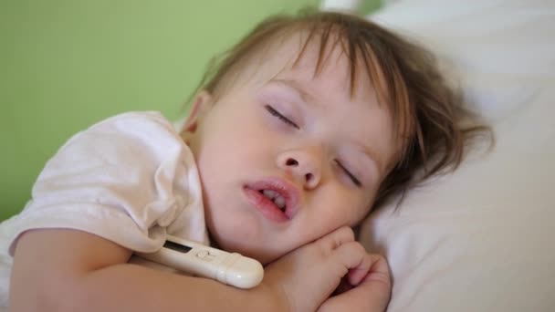 La température de l'enfant est mesurée avec un thermomètre dans la salle d'hôpital. Gros plan. Bébé dort à l'hôpital sur un lit blanc
. - Séquence, vidéo