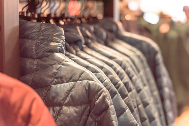 Γκρο πλαν το χειμώνα κάτω σε κρεμάστρα ρούχων στο κατάστημα American ρούχα για την ύπαιθρο. Μόνωση μοντέρνα μπουφάν με φερμουάρ. - Φωτογραφία, εικόνα