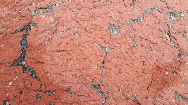 Rot gefärbte beschädigte Straße oder gepflasterter Weg mit Rissen verschiedener Schädel. Geknackte Textur mit Kopierraum für Text und Nachrichten - Foto, Bild