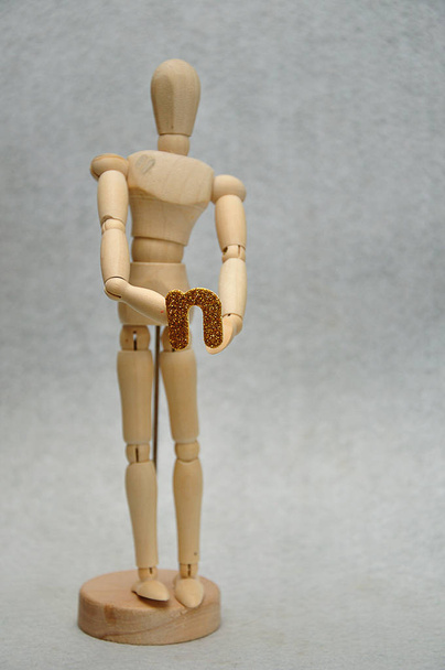 A wooden mannequin holding a letter n - Фото, изображение