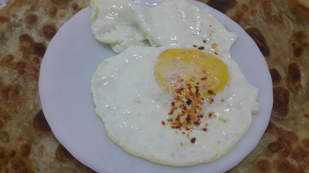 Widok z góry na omlet z jajkiem lub jajkiem na białym spodzie lub talerzu podawanym z grzbietami. - Zdjęcie, obraz