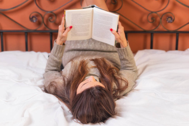 Femme couchée au lit lisant un livre
 - Photo, image