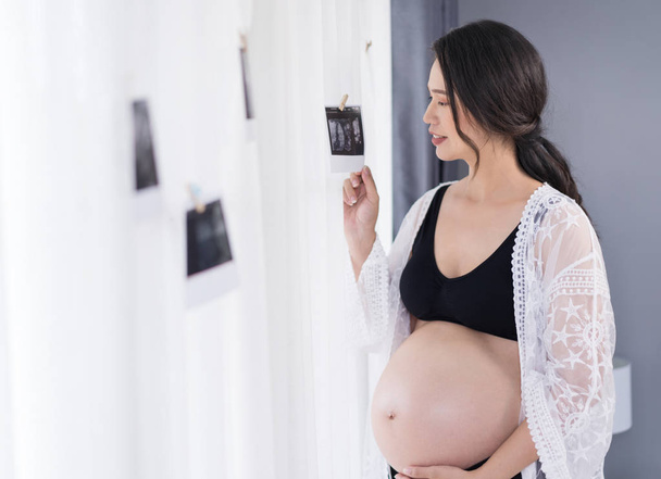 happy pregnant woman looking ultrasound scan photo  - Zdjęcie, obraz