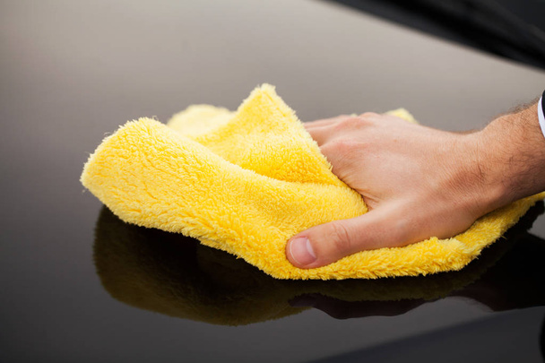 Clining car. Wiping panel of a luxury car with yellow microfiber, close-up view - Fotoğraf, Görsel