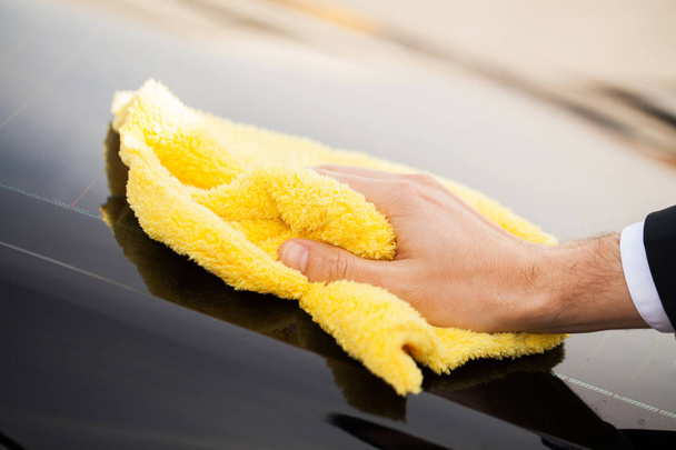 Clining car. Wiping panel of a luxury car with yellow microfiber, close-up view - Foto, Imagem