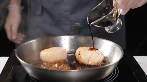 Zeevruchten in restaurant. Vegetarische concept. Professionele chef-kok in handschoenen gieten saus op Sint-jakobsschelpen in koekenpan. Slow-motion. HD - Video