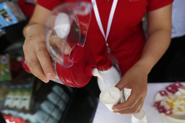 An employee fills up cups with Swiss milk during the Swiss Week in Shanghai, China, 13 May 2017 - Photo, Image