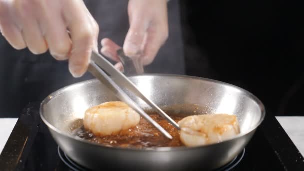 Cocinar mariscos. concepto de comida saludable. Chef profesional en guantes cocinando vieiras convirtiéndolas con alicates culinarios en cámara lenta. hd
 - Metraje, vídeo